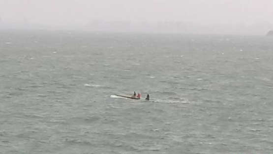 烟台海域，一艘船舶翻扣，3名遇险人员站在翻扣船体上呼救。